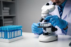 Professional scientist using microscope while working on medical research in science laboratory. photo