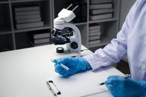 Close up view of scientist researcher taking note while testing substances in laboratory. photo