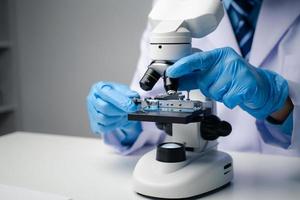 Professional scientist using microscope while working on medical research in science laboratory. photo