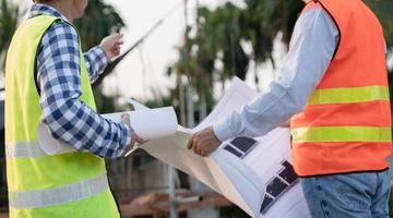 inspector or engineer is inspecting construction and quality assurance new house using a blue print. Engineer or architects or contactor work to build the house before handing it over to the homeowner photo