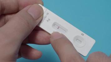 POV of Man hands using Rapid antigen test kit or ATK and blue background. video