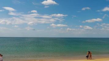 PHUKET, THAILAND NOVEMBER 30, 2019 - Passenger jet airliner flies over the sea to land at Phuket airport HKT. People take pictures in front of a flying plane video