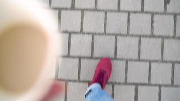 Top view of male and female legs strolling along the sidewalk. Woman drinking coffee video