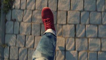 Top view of mens legs in red sneakers walking along the sidewalk video