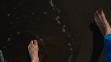 Top view of couple strolling together at the black volcanic sand at ocean beach video