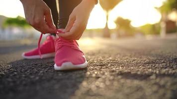 stänga upp av kvinna kvitt sko skosnören och löpning längs de handflatan aveny på solnedgång video