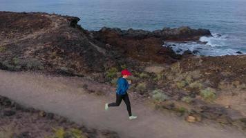 Aerial view of woman runs along the oceanfront nature reserve at sunrise. Healthy active lifestyle video