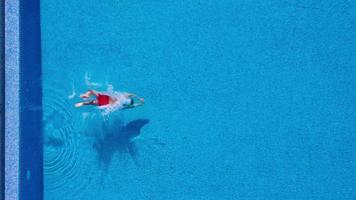 Antenne Aussicht von Mann im rot kurze Hose schwimmt im das Schwimmbad. schleppend Bewegung video