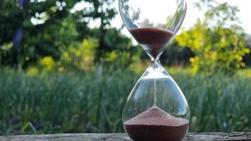 Hourglass on a wooden table in the garden. Time concept. video