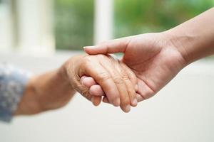 Asian young boy holding old grandmother woman hand together with love and care. photo