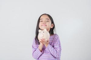 niña asiática ahorrando dinero en una alcancía, aprendiendo a ahorrar, los niños ahorran dinero para la educación futura. concepto de dinero, finanzas, seguros y personas foto