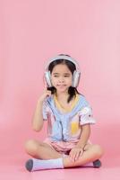Asia little girl cute put on headphones have video call distant class with teacher using laptop, study online on computer, homeschooling concept photo