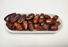 pile of dates fruit in white styrofoam tray, white background photo