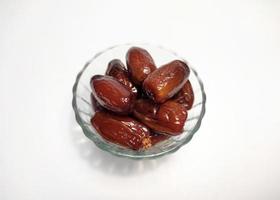 pile of dates in transparent bowl, white background photo