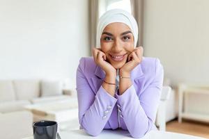 de cerca retrato de musulmán mujer de negocios vistiendo hijab mira a cámara y sonrisas hermosa mujer vistiendo tradicional Pañuelo. exitoso empoderado árabe mujer. foto