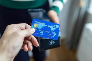 Contactless payment concept, female holding credit card near nfc technology on counter, client make transaction pay bill on terminal rfid cashier machine in restaurant store, close up view photo