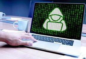 Hacker hand pressing keyboard laptop with icon hacker and green binary numeral background on display photo