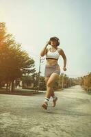 woman wearing headphone running in home village park photo