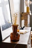 Brown glass vase with dried flowers in the interior of a modern house photo