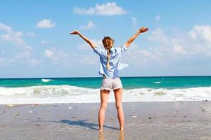 el concepto de libertad y independencia - un contento niña soportes en un arenoso playa y foto