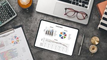 Tablet with charts and reports on office desk workplace. Top view flat lay photo