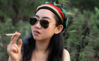 Yong Asia woman smoking marijuana at cannabis tree plant background photo