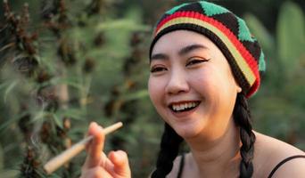yong Asia mujer de fumar marijuana a canabis árbol planta antecedentes foto