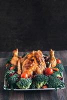 Roasted chicken with vegetables on wooden table photo