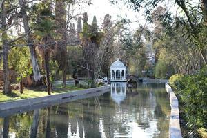 New Athos. Abkhazia.March, 26, 2023. Seaside park at sunset in early spring.View of the pond, gazebo and bird house. photo