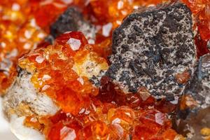 macro mineral stone Spessartine, orange, red garnet with quartz on white background photo