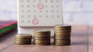 Stack of coins and calendar on white background video