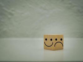 A wooden cube with a smiley or happy face. and frown or dissatisfaction Each side chooses the expression of the face. photo