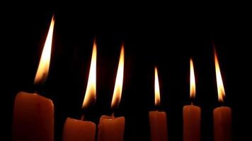 Grouped candles and high fires on black background, large fire of grouped candles illuminates darkness atmosphere, selective focus video