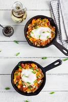Shakshouka in frying pan. Fried eggs with vegetables, tomato, pepper, pumpkin and onion. Top view photo