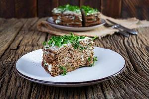 Liver cake on wooden background. Sliced layered liver cake with mayonnaise photo