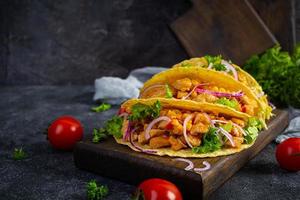 tacos mexicanos con tortilla de maíz. tortilla con carne de pollo, maíz, lechuga y cebolla foto