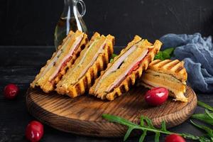 Club sandwich with ham, cheese, tomato and salad. Grilled sandwich with dried tomatoes bread photo