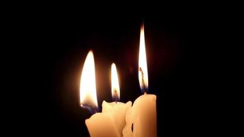 Waxes burn and melt, Burning candles on black background illuminates around and bends due to melt, selective focus video