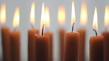 Candles burning in a lightly lit environment, many candles create a dim atmosphere in a weak light atmosphere , selective focus video