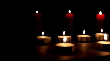 Many candles burning together on black background and have an abstract atmosphere, thin and thick colored candles create a dim environment, selective focus video