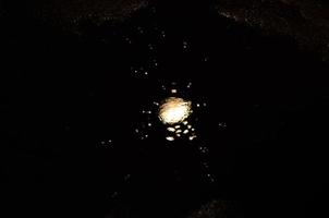 Light is reflected in a puddle. Blurred light in the puddle, dark night. Splashes. photo