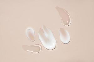 cosmetic smears of creamy and gel texture on a pastel beige background, top view photo