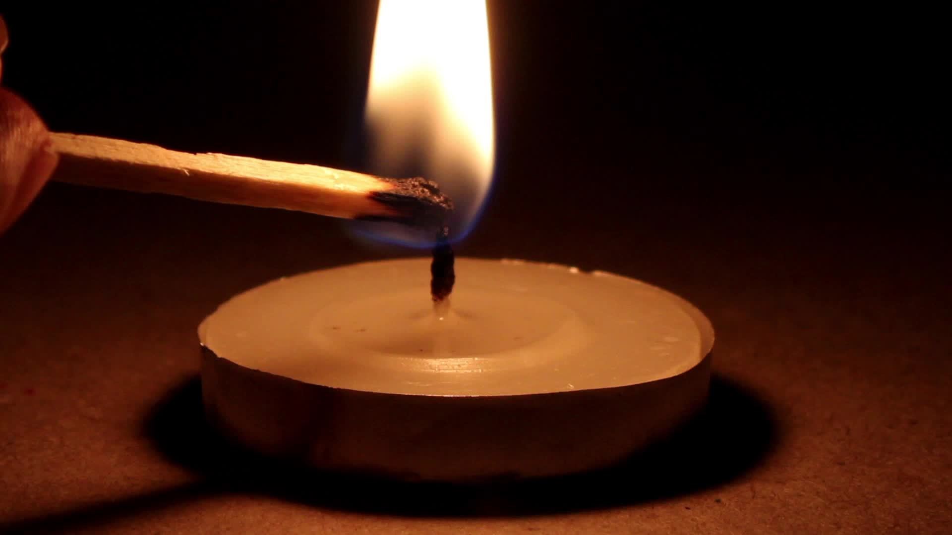 Lighting candle with a black background, candle burning with a match on