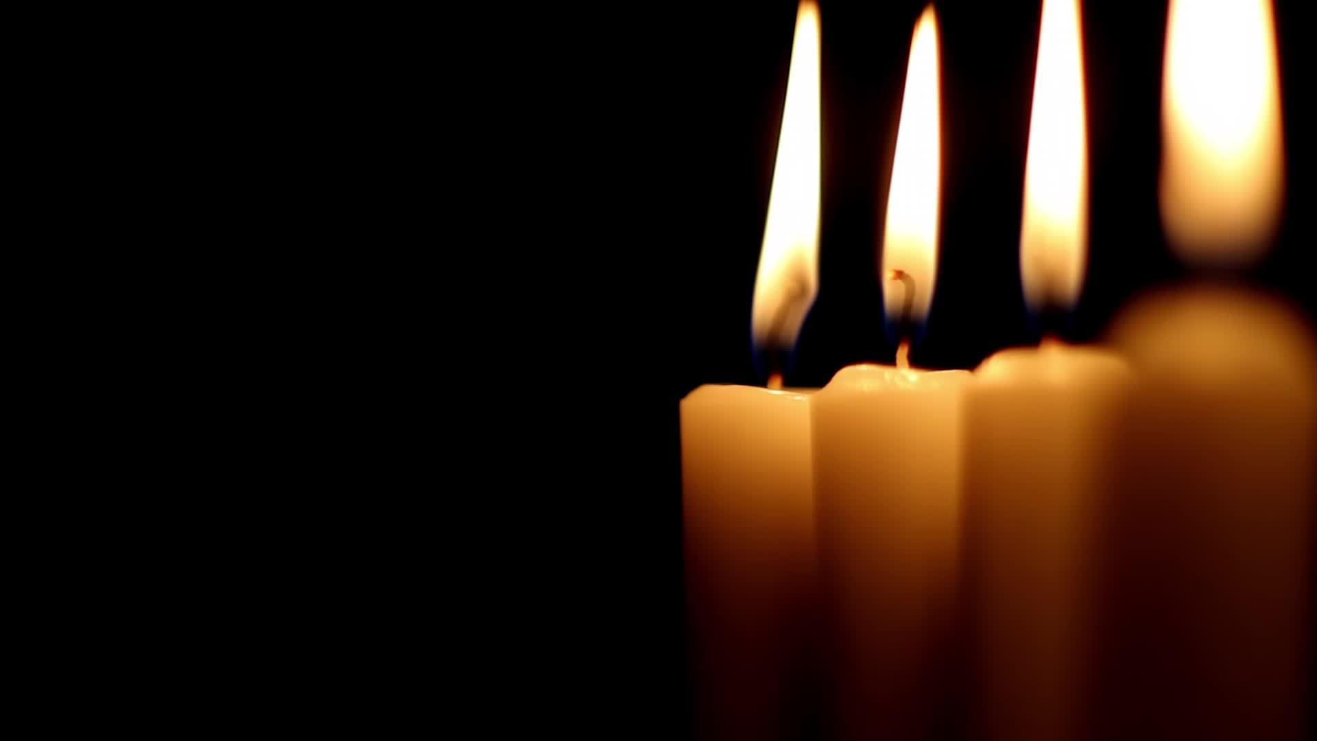 Candles burning at a dark night, several candles in a row are lit