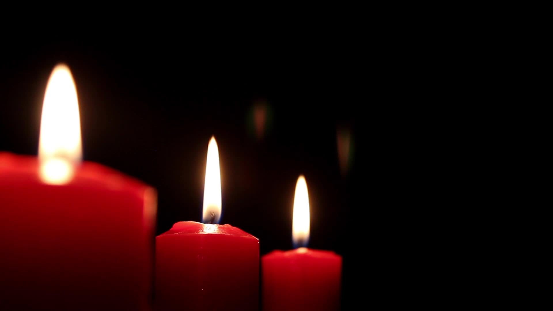 Burning red candles on black background, fire of thick red candles