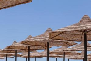 sunshade straw beach umbrellas against blue sky photo