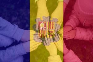 Hands of kids on background of Andorra flag. Andorran patriotism and unity concept. photo