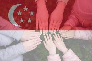 Hands of kids on background of Singapore flag. Singaporean patriotism and unity concept. photo