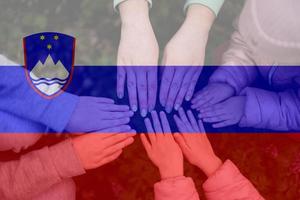 Hands of kids on background of Slovenia flag. Slovenian patriotism and unity concept. photo