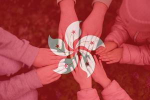 Hands of kids on background of Hong Kong  flag. Hongkonger patriotism and unity concept. photo